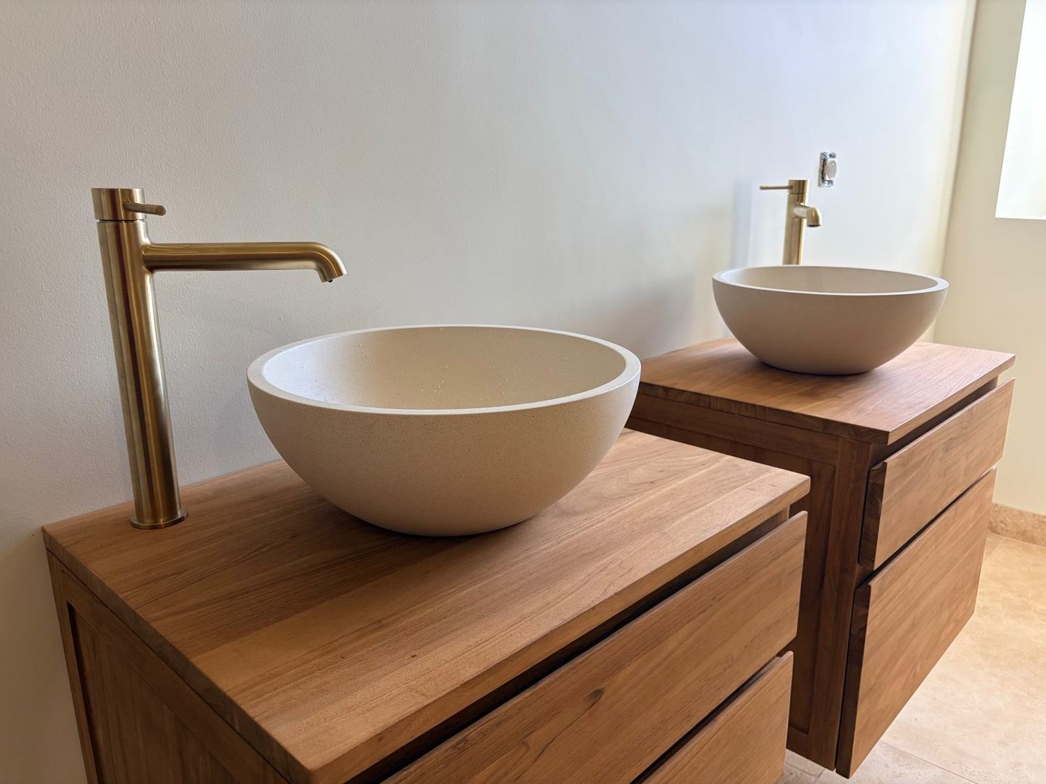 Vasques en pierre sur meubles en bois et robinetterie dorée