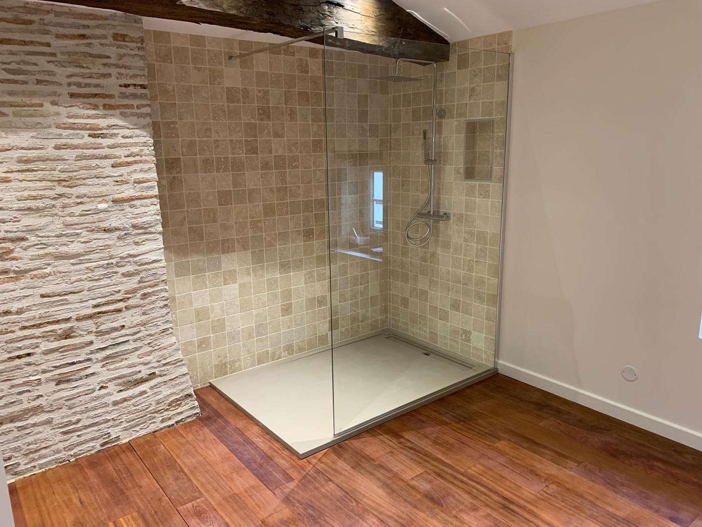 Douche à l'italienne en travertin avec paroi en verre