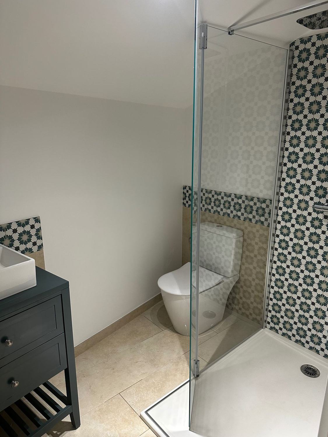 Salle de bain avec douche à vitre et carrelage à motifs