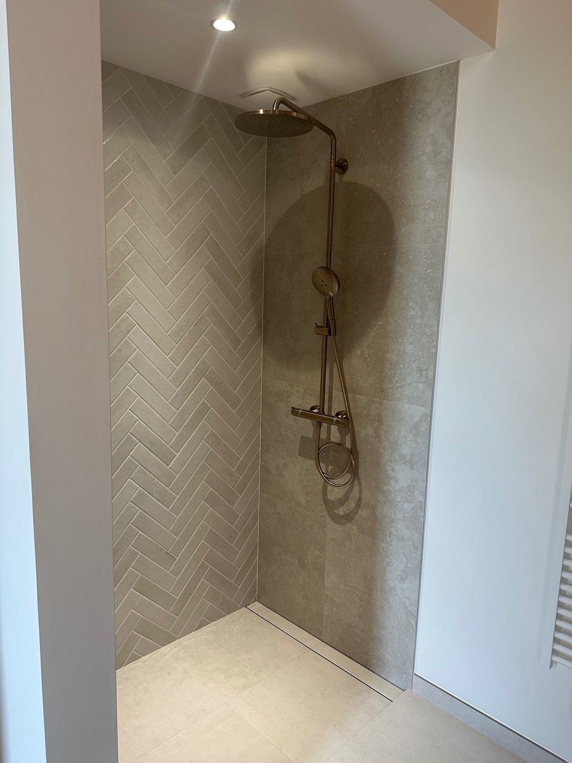 Douche à l'italienne avec carrelage chevrons et robinetterie cuivrée